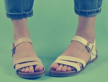 Kot pantolon giymiş ve izole üzerinde mavi arka plan poz sandalet ayakkabılı kadın bacaklar. Kadın moda. Kadın yaz footwea