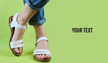 Kot pantolon giymiş ve poz sandalet ayakkabılı kadın bacakları geen özgeçmişlerine izole. Kadın moda. Kadın yaz ayakkabı. Kopya alanı