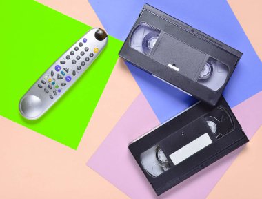 Pastel renkli bir arka plan üzerinde uzak, video kaset. Retro eğlence teknoloji 80s. Minimalizm eğilim. Üstten görünüm