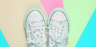 Pastel renkli bir arka plan üzerinde beyaz dantel ile eski retro spor ayakkabı. Minimalizm. Top Vie