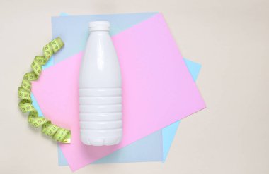 Yoğurt cetvel renkli kağıt arka plan, üstten görünüm üzerinde plastik şişe. Ağırlık kaybetme kavramı