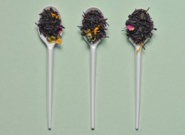 Plastik kaşık kuru çay yaprakları mor bir arka plan üzerinde