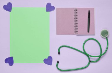 Not defteri kalem, stetoskop, mavi kopya ile uzay pastel pembe bir arka plan üzerinde dekoratif yürekleri. Tıbbi kavramı. Üstten görünüm. Minimalis