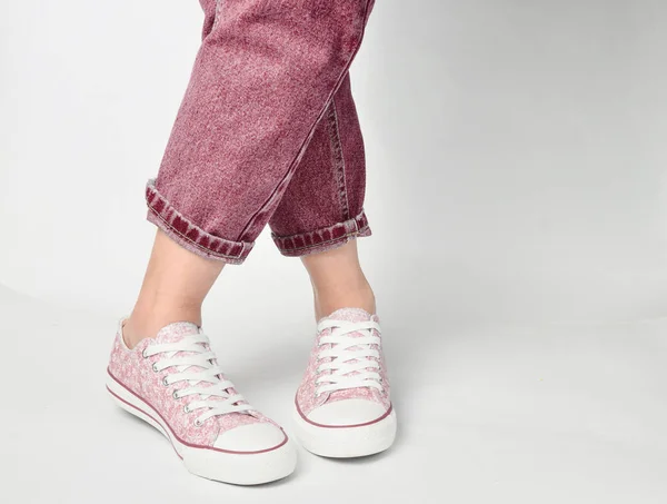 Vrouwelijke Benen Kortom Jeans Sneakers Staan Een Witte Pagina — Stockfoto