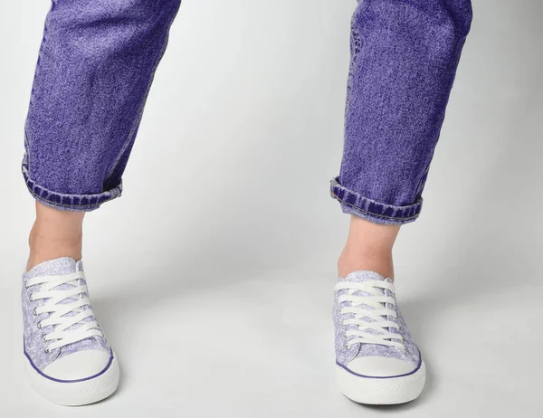 Vrouwelijke Benen Kortom Jeans Sneakers Staan Een Witte Pagina — Stockfoto