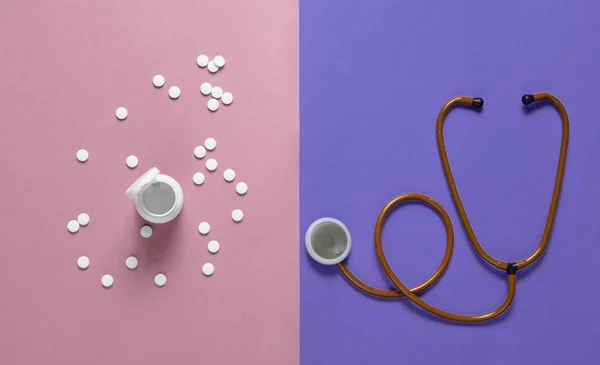 听诊器和瓶与药丸上的彩色背景 医疗概念 顶级视图 — 图库照片