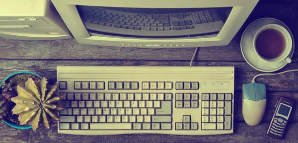 Retro stationary computer on a rustic wooden desk, vintage workspace. Monitor, keyboard, computer mouse, top view, flat la