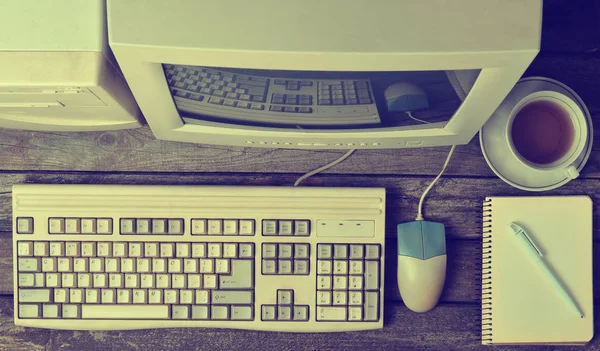 Retro stationary computer on a rustic wooden desk, vintage workspace. Monitor, keyboard, computer mouse, top view, flat la