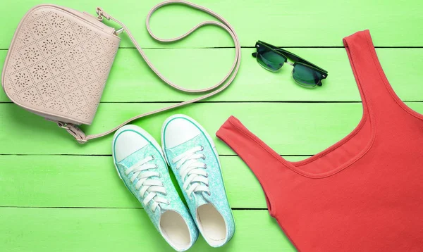 Rotes Shirt Turnschuhe Ledertasche Sonnenbrille Auf Einem Blauen Holztisch Damenbekleidung — Stockfoto