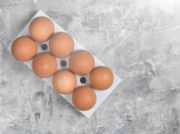 Plastic tray with chicken eggs on a gray concrete background. Top Vie