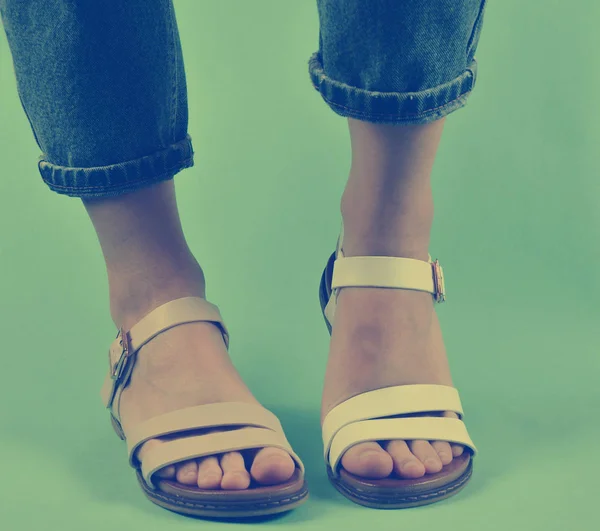 Vrouwelijke Benen Jeans Gekleed Geschoeid Sandalen Poseren Geïsoleerd Blauwe Achtergrond — Stockfoto