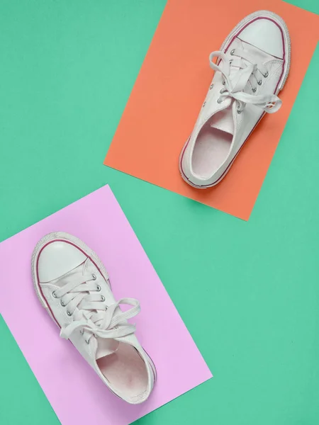 Retro sneakers step on a colored paper background. Top view