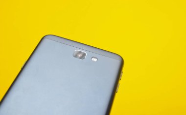 Sarı bir arka plan bir kamera ile yeni bir smartphone arkasında. Uzay kopyalayın. Modern teknoloji.