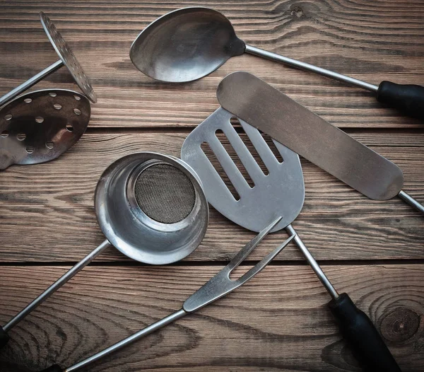 Kitchen tools for cooking consisting of a sieve, fork, ladle, spoon, shovel for frying on a wooden table. Top view.