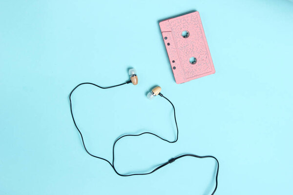 Vacuum earphones on  blue pastel background. Retro media, music lover, 80s. Top view, flat la