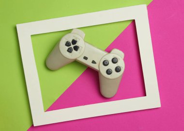 Gamepad renkli bir arka plan üzerinde beyaz bir çerçeve içinde. Üstten Görünüm, minimalizm