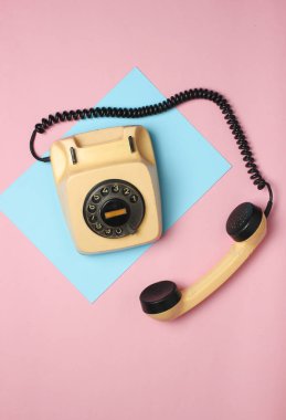 Pastel renkli bir arka plan üzerinde 80s Retro döner telefondan. Üstten Görünüm, minimalis
