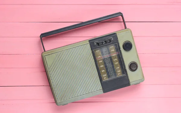 Retro old radio receiver on a pink wooden background. Top view. Outdated technolog