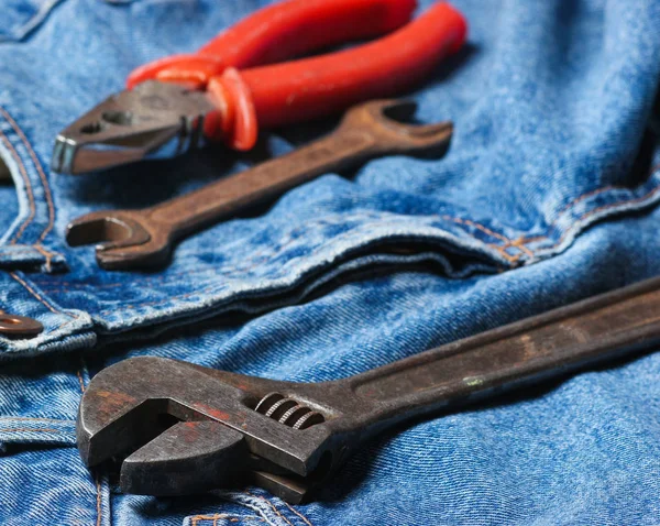 Work tool on blue jeans. Pliers, wrench, adjustable wrenc