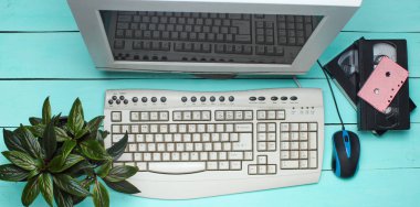 Mavi ahşap masa Retro bilgisayarda. Vie monitör, klavye, pc fare, pot bitki, video kaset, Ses Kaseti, üst