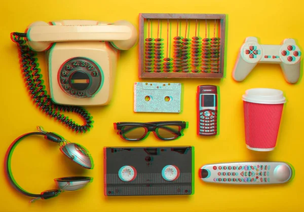 黄色の背景にレトロなオブジェクト ロータリー電話 オーディオカセット ビデオカセット ゲームパッド メガネ テレビリモコン ヘッドホン プッシュボタン電話 過去のアナログメディア技術 — ストック写真