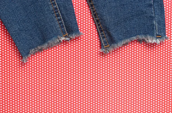 Ragged jeans on red creative backgroundin polka dot. Top view