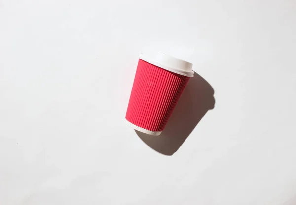 Paper cup of coffee on white background. Photo with shadows, hard light, top vie