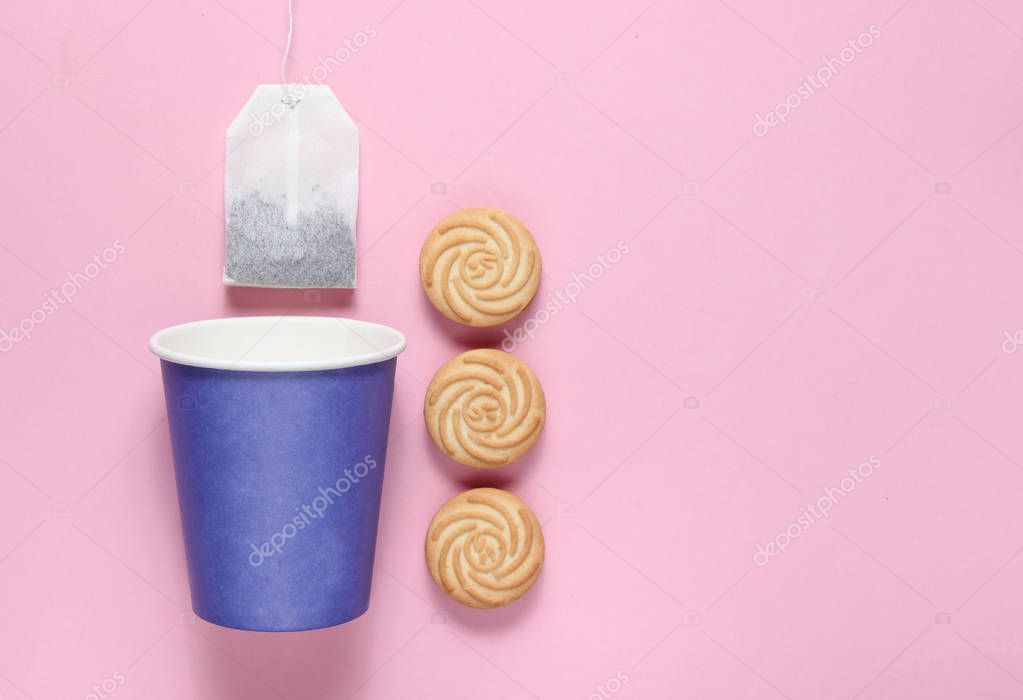 Empty disposable paper cup for tea, tea bag, cookies on pink pastel background, top view, minimalis