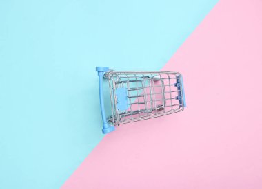 Renkli pastel arka planda alışveriş için mini alışveriş arabası, tüketici kavramı, Minimalizm, üst görünüm