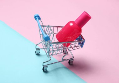 Mavi pembe pastel arka planda bir alışveriş sepeti parfüm şişesi. Minimalizm, güzellik kavramı, aksesuar