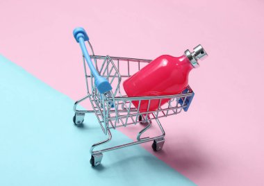 Mavi pembe pastel arka planda bir alışveriş sepeti parfüm şişesi. Minimalizm, güzellik kavramı, aksesuar