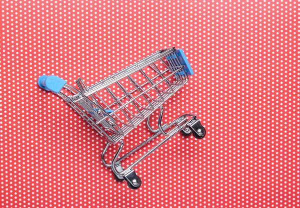 Mini shopping trolley for shopping on red background, consumer concept, minimalism, top view