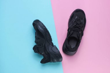 Pastel arka planda siyah spor ayakkabılar. Üst görünüm, minimalizm