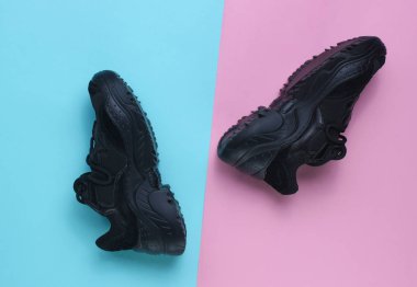 Pastel arka planda siyah spor ayakkabılar. Üst görünüm, minimalizm