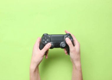 Yeşil arka planda gamepad kullanmak için eller. Üstte görüntü