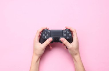 Eller pembe arka plan üzerinde gamepad kullanmak için. Üst görünüm, minimalizm 
