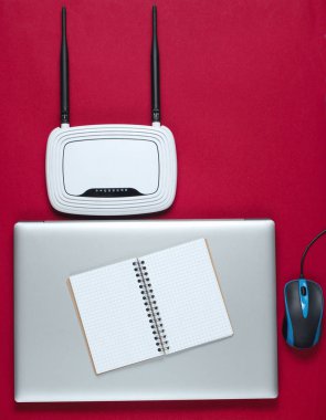 Kablosuz ağ yönlendirici, dizüstü bilgisayar, bilgisayar faresi, kırmızı arka planda not defteri. Üst görünüm