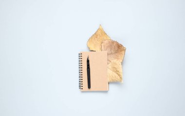 Kalemli defter, gri bir arka plan üzerinde sonbahar yaprakları. Sonbahar ilhamı, yazma. Üst görünüm, minimalizm