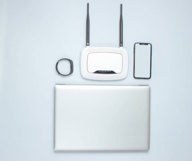 Dizüstü bilgisayar, antenli Wi-Fi yönlendirici, akıllı telefon, gri arka planda akıllı saat. Online çalışma, modern gadget'lar, internet çağı. Top vie