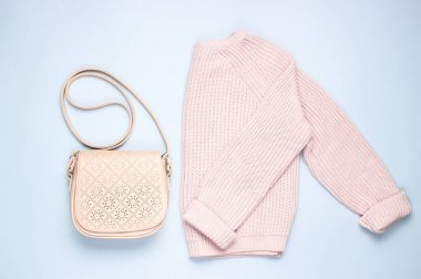 Gri bir arka plan üzerinde şık pembe pastel örme kazak deri çanta. Üstte görüntü