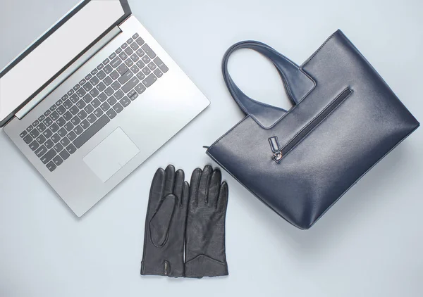 Leather bag, gloves, laptop on a gray background. Business and fashion. Top view, minimalism