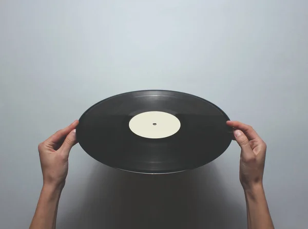 女性の手は灰色の背景にレトロなビニールレコードを回転させます トップビュー ミニマリズム — ストック写真