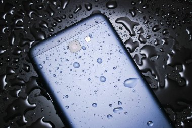 Su damlaları ile siyah bir arka plan üzerinde su damlaları ile akıllı telefonun arka tarafında. Akıllı telefonunuzu wate'den koruyun