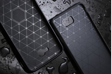 Su damlaları ile siyah arka plan üzerinde koruyucu akıllı telefon kılıfları. Akıllı telefonunuzu wate'den koruyun