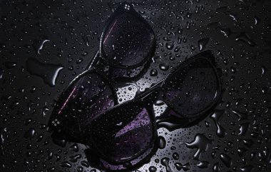 siyah bir arka plan üzerinde su damlaları ile iki çift güneş gözlüğü