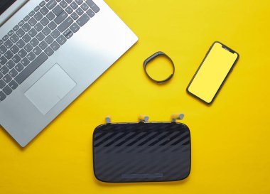 Dizüstü bilgisayar, wi-fi yönlendirici, akıllı telefon, akıllı izci, sarı arka plan. Online çalışma, modern peopl için gadget'lar