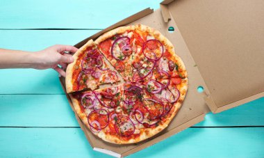 El mavi beton masa üzerinde kutusunda pizza bir parça alır. Top vie