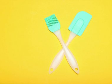 Mutfak pasta silikon seti (spatula ve fırça) sarı bir arka plan üzerinde. Üstgörünüm, minimalis