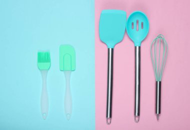 Mutfak gereçleri seti: mutfak fırçası, çırpma teli, pembe mavi pastel arka plan üzerinde spatula. Üstgörünüm, minimalis