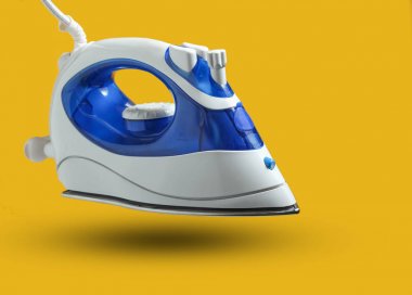 Sarı bir arka plan üzerinde izole ütü için modern demir. Yükselme, minimalizm. Gölgeli fotoğraf